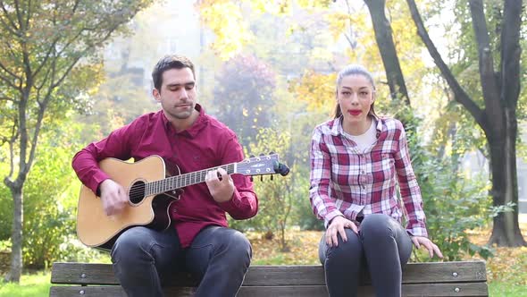 Beautiful Brunette Woman Singing And Man Playing Guitar In Park 2