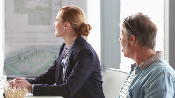 Profile Of Man And Woman Talking With Colleague In Conference Room