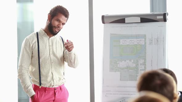 Handsome Man Pointing At Flipchart While Giving Presentation To His Colleagues