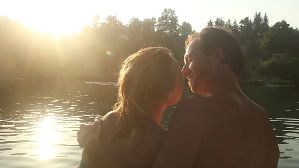 Romantic Couple Kissing While Sitting By The River At Sunset 1