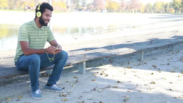 Handsome Man With Headphones Listening To Music On Smartphone At Park
