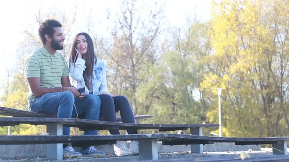 Happy Couple Sharing Earphones While Listening To Music At Park