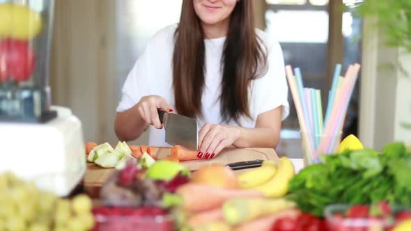 Woman Cutting Carrot Into Slices On Wooden Board