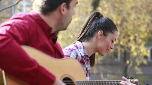 Couple Singing And Playing Guitar In Park 3