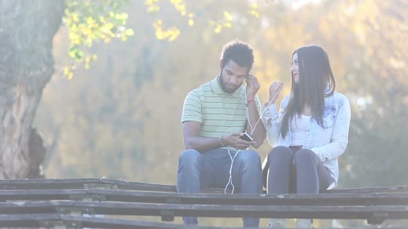 Couple Starting To Listen To Music On Smartphone, Sharing Earphones