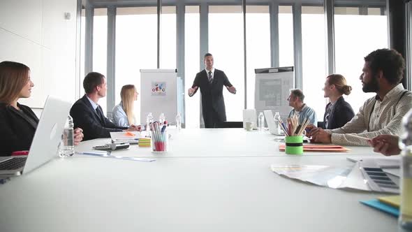 Smiling Businessman Giving Presentation To Colleagues In Conference Room 1