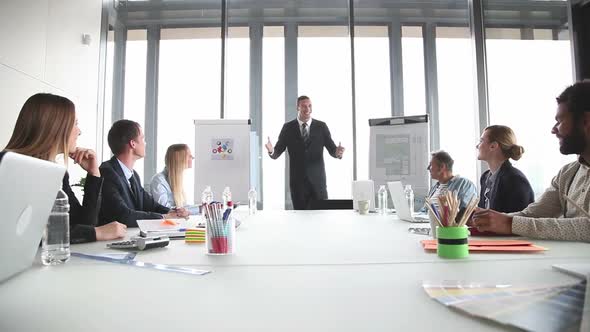 Smiling Businessman Giving Presentation To Colleagues In Conference Room 2