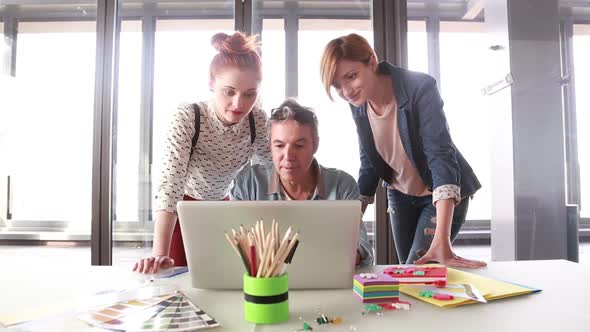 Creative Director Looking At Laptop With His Team And Discussing Plans 1