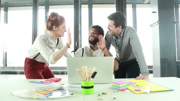 Male Creative Executive High-Fiving With Colleagues In Office 2