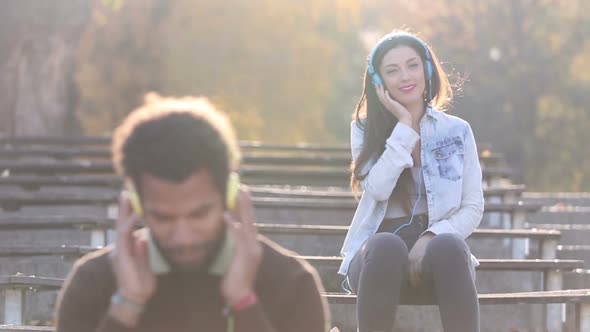 Man And Woman Listening To Music On Headphones At The Park 2