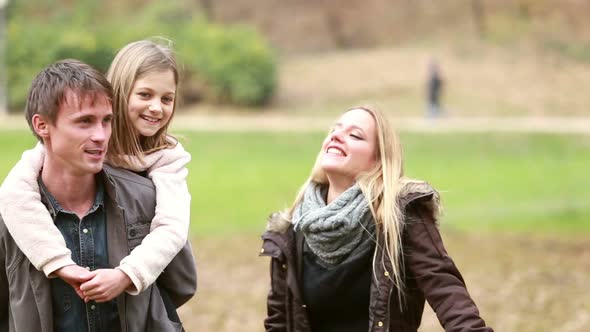 Family Having Fun In Park, Father Giving Daughter Piggyback Ride