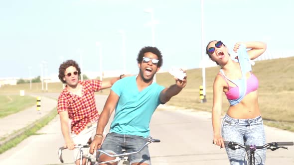 Three Young Adults Cycling And Taking Selfies With Phone, Graded