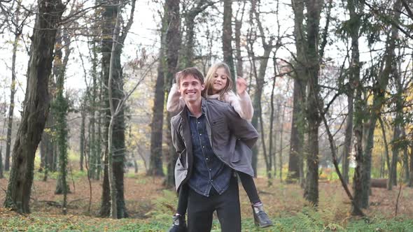 Father Carrying Daughter On Back And She Is Throwing Leaves In The Air 2