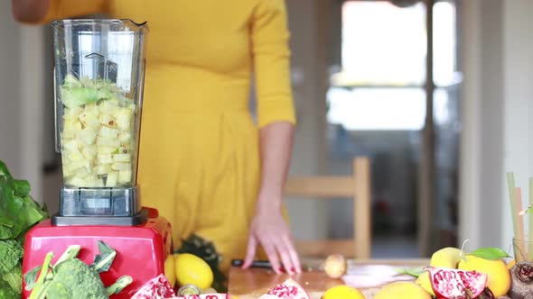 Woman Pouring Water In Blender With Pineapple And Avocado