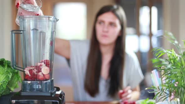 Woman Pouring Water Into Blender With Fruits