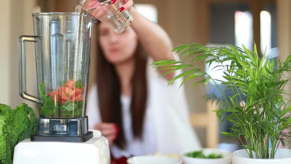 Woman Putting Carrot And Pouring Water Into Blender