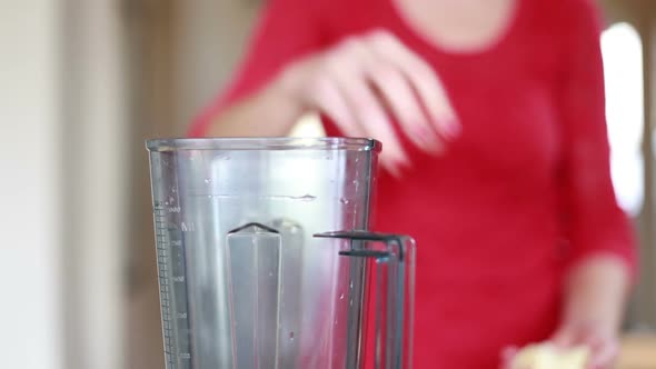 Woman Putting Orange Into Blender