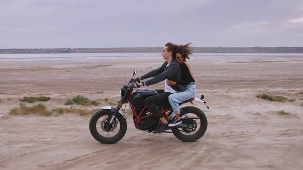 Young Couple Riding on Vintage Motorcycles During Cloudy Sunset on Beach Slow Motion