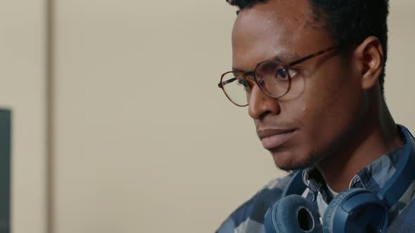 Portrait of African American Database Developer with Glasses Working Focused Looking at Computer