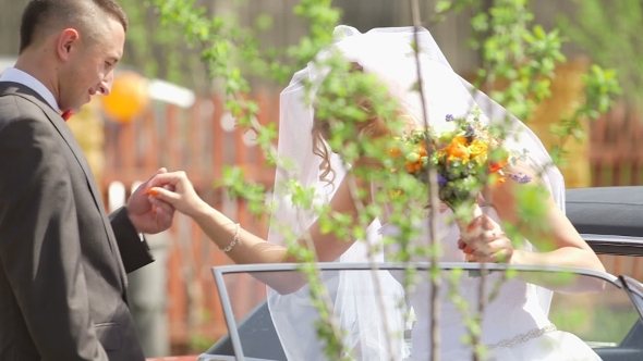 Groom Assisting Bride In Disembarking Car