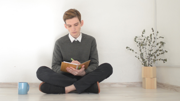 Young Man Writing, while Sitting on Floor