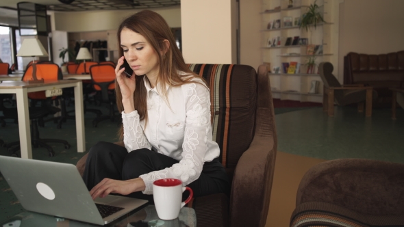 Woman Working With Laptop And Talking On The Phone