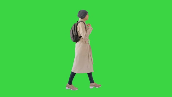 Woman with Backpack in Outdoor Clothes Walking and Coughing on a Green Screen, Chroma Key.