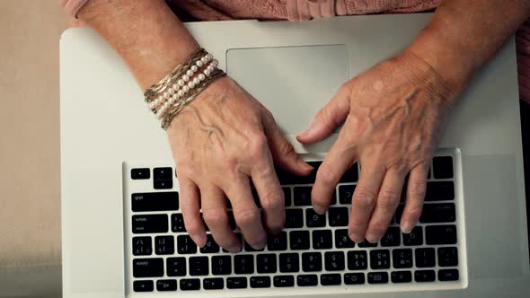 Elderly Hands Typing On Notebook Keyboard And Writing Message. Senior Woman Surfing Browser.