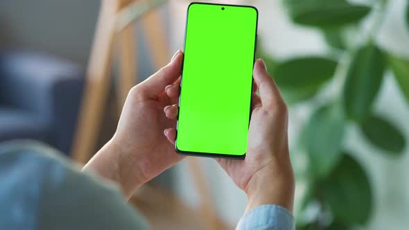 Woman at Home Using Smartphone with Green Mockup Screen in Vertical Mode