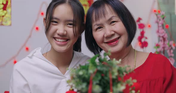 Asian Senior Woman And Niece Decorate House For Chinese New Year Celebrations.