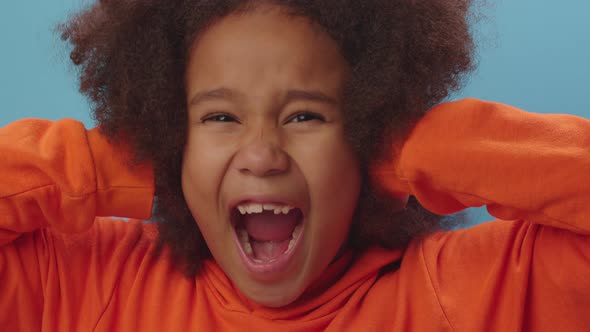 Pretty African American girl closes her ears with hands and screaming 'no'