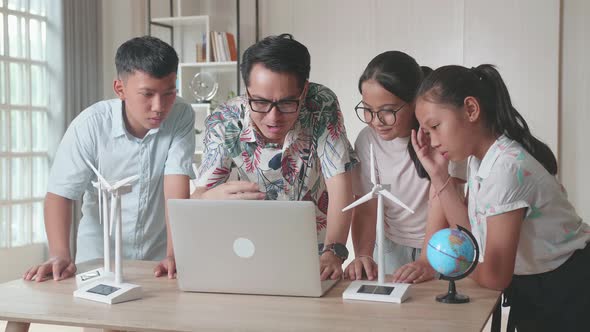 Asian Teacher Use Laptop Computer Explains To A Brilliant Young Children How Wind Turbines Work