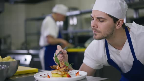 Concentrated Young Cook Decorating Seafood with Greenery in Slow Motion Turning Plate with Dish