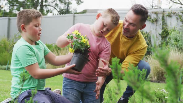 Happy caucasian father with two sons gardening together in garden