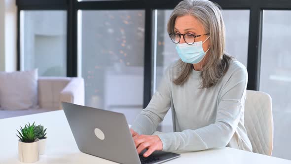 Grayhaired Mature Businesswoman Wearing Protective Medical Mask Using Laptop