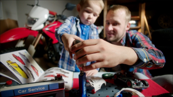 Father Helping Son With Toy Electric Screwdriver