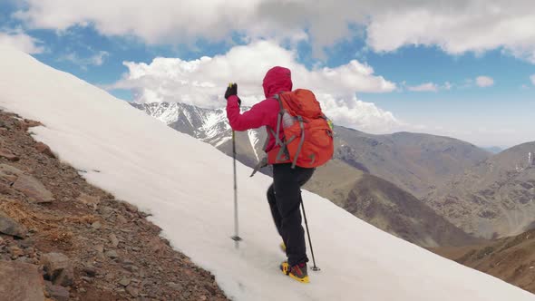 Alpinist girl in crampons ascending the mountain in High Atlas, Morocco