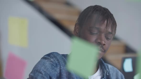 Young Thoughtful Man Sticking Adhesive Notes on Glass Door in Home Office