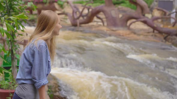 A Young Woman Visits Waterfall in Mountains. Travel To Dalat Concept