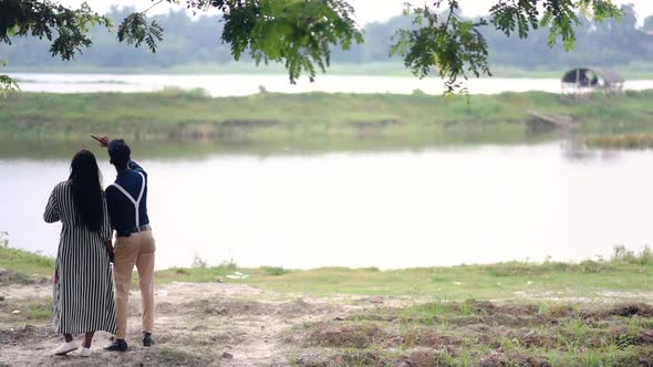 Happy and Fashionable romantic couple in love in their honeymoon near a lake and forest, camera pan