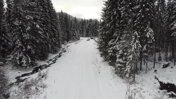 Aerial Over Snow Covered Road With Suv In A Forest