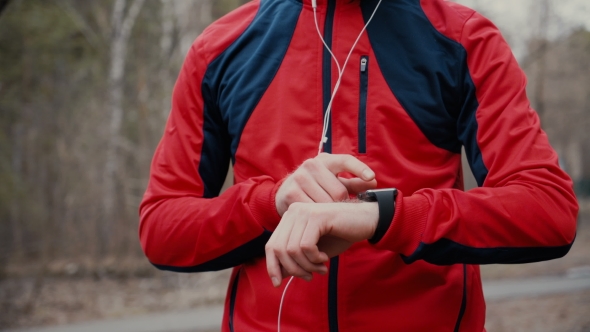 Man Running In Forest Woods Training And Look At Smart Watches.