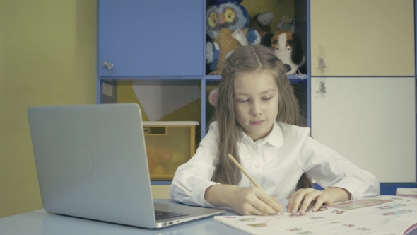 Young Girl Using a Laptop And Doing Homework In School