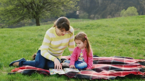 Attractive Young Woman Reads a Book a Little Girl