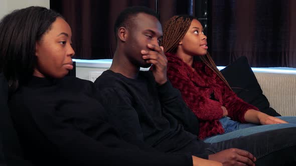 Three African Friends Watch Television in Living Room and They Are Angry