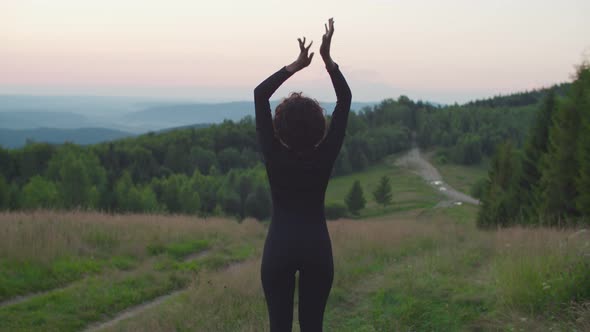 Rear View of African American Woman Doing Arm Stretching Exercise in Mountains at Dawn