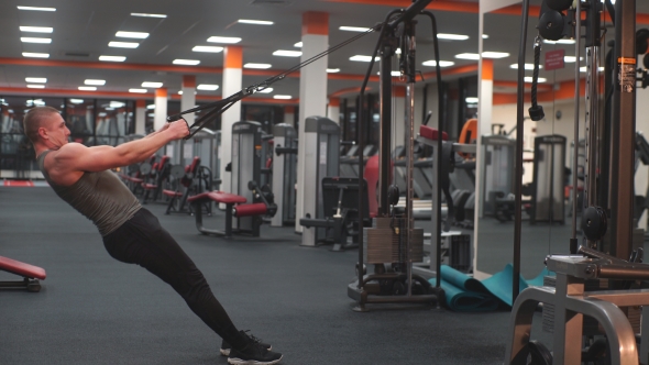 A Man Makes Multifunctional Exercises In The Simulator