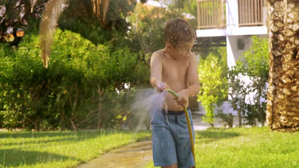 Boy Watering the Lawn and Getting Wet