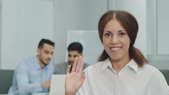 Smiling Female Leader Manager Coach Speaker Looking at Camera Waving Hello