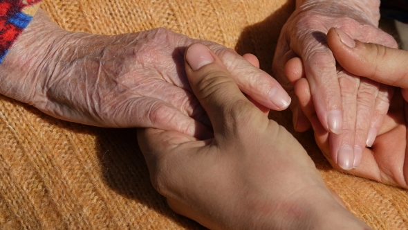 A Young Male Hands Comforting An Elderly Pair Of Hands